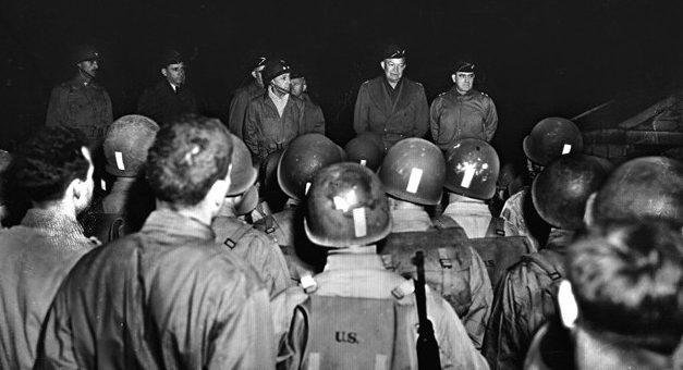 General Dwight D. Eisenhower (center) addresses soldiers of the 116th Regiment, 29th Division during training exercises on February 4, 1944. Eisenhower is flanked by Major General Charles Gerhardt (left), commander of the 29th Division, and Major General Leonard Gerow (right), commander of the U.S. Army’s V Corps.