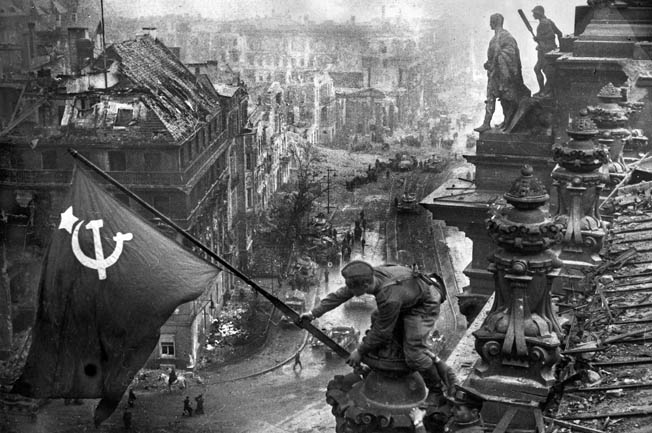 WORLD WAR II: BERLIN, 1945. The Soviet soldier Meliton Kantarija hoisting the Red Flag on the Reichstag building in Berlin, May 1945. Photographed by Yevgeny Khaldei. Full credit: Voller Ernst - ullstein bild / The Granger Collection.