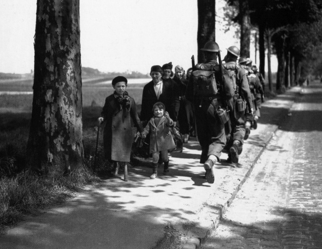 Fleeing the oncoming Germans, French refugees seek safety near the village of Louvain. Thousands of displaced civilians clogged roads and impeded the movement of Allied troops vainly attempting to stem the Nazi tide.