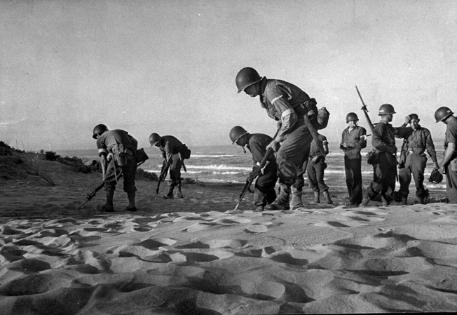 American combat engineers using their bayonets to locate and remove mines ahead of troops coming ashore during the invasion of Sicily. (Photo by Bob Landry//Time Life Pictures/Getty Images)