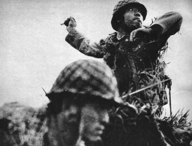 A Japanese soldier rises up to hurl a grenade while his comrade faces the enemy to his front. This photo was taken during the six months of bitter fighting on the island of Guadalcanal. 