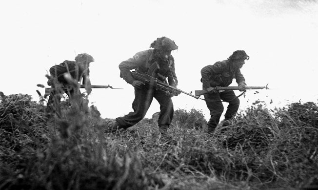 Three British infantrymen advance cautiously during a probe of German positions around the villages of Baron and Eterville southwest of Caen.