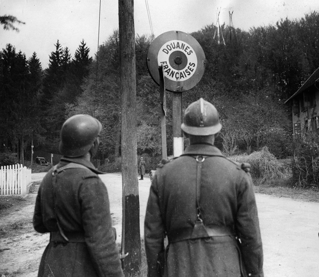 French border guards inspect a sign from inside Germany. Hostile gunfire was a rare occurrence as both sides went about their business until Hitler launched his assault on France and the Low Countries on May 10, 1940.
