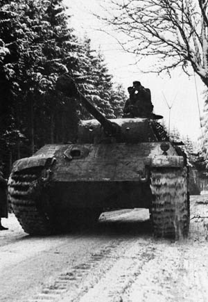 Its commander riding in the open air for better visibility, a German panzer rolls into Belgium in December 1944.