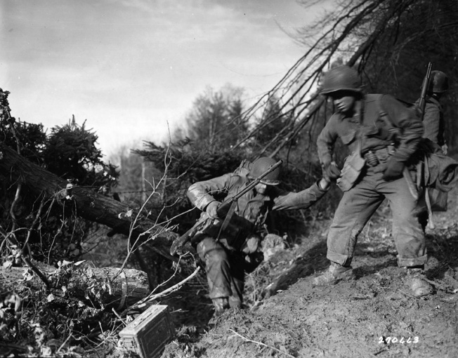 American Pfc. Benny Barrow gives a comrade a hand up during the bitter fighting in the Hurtgen Forest on November 18, 1944.