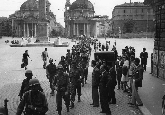 En route to the front, sodliers of the 85th Infantry Division march through the Piazza Del Popolo in the liberated Italian capital of Rome.