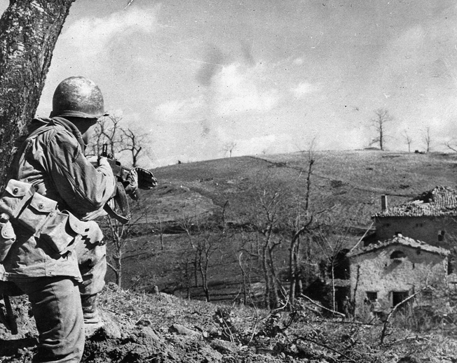 As his comrades root out enemy combatants from a house in Bologna, a U.S. soldier provides cover.