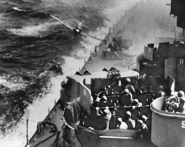 This famous photo depicts the moment of impact as a Japanese Kamikaze hits the hull of the battleship USS Missouri as sailors continue to service their antiaircraft weapons. The A6M2 Zero fighter glanced off the battleship and crashed into the sea moments after the photo was taken.