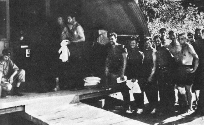 These sailors who survived the sinking of the light cruiser Helena during the Battle of Kula Gulf made their way to the island of Vella Lavella and were subsequently rescued. In this photograph, they are being issued new clothing.