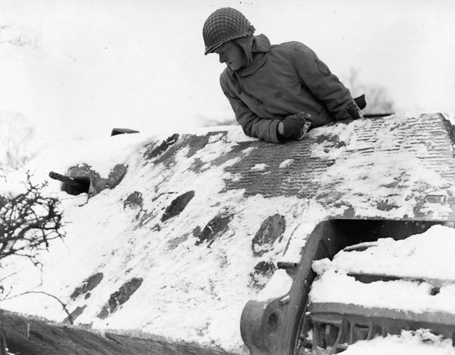 Sergeant George Meyer looks in disbelief at the scars from six direct hits against an enemy Mark VI Tiger tank. The thick armor of the Tiger withstood the successive impacts during the desperate fighting in the Bulge.