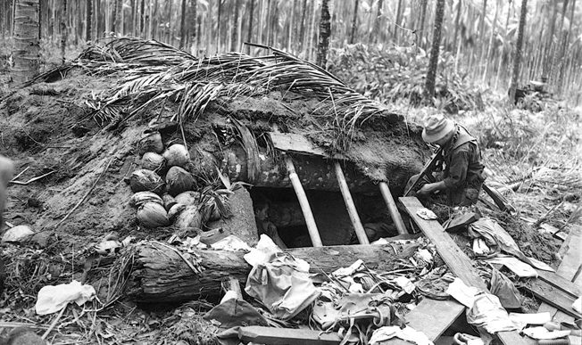 Peering into a pillbox formerly occupied by the Japanese enemy on December 21, 1942, men of the 32nd Infantry Division solidify hard-won territorial gains on New Guinea. The Japanese proved to be a tenacious enemy, and months of bitter fighting lay ahead. 