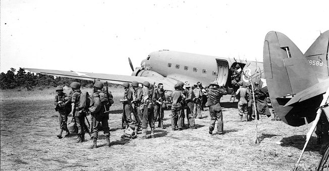 Troops of the 127th Infantry Regiment, 32nd Division, board Douglas C-47 transport aircraft at Dubadura air strip, eight miles from Buna. The soldiers were involved in a large-scale relocation of troops by air during the campaign to secure New Guinea from the Japanese.