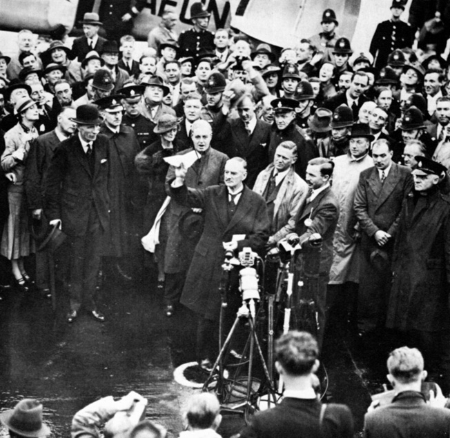 Neville Chamberlain stands in front of a welcoming crowd upon his return from negotiating with Hitler in Munich.