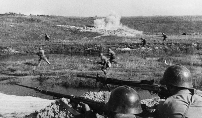A German artillery shell explodes as Soviet soldiers advance rapidly across open ground during a counterattack against enemy thrusts toward Leningrad.