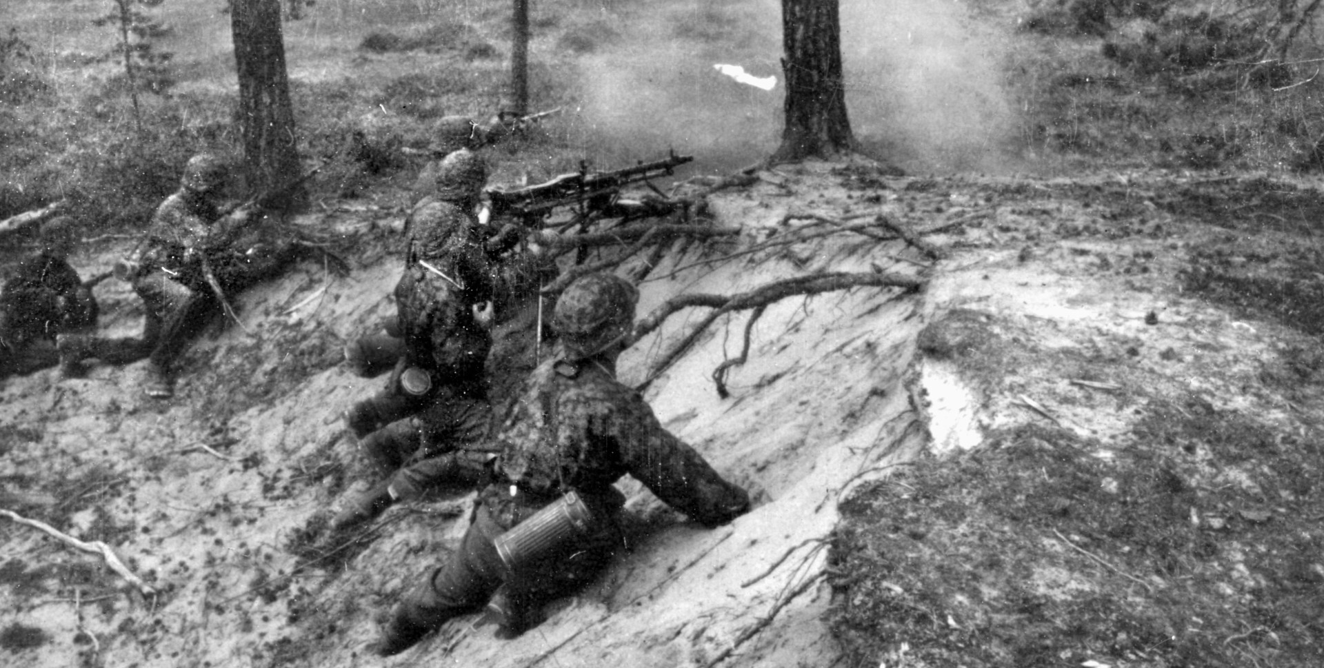 Wispy smoke rises from the barrel of a German machine gun during a heated engagement with Soviet troops near Leningrad. These are Waffen SS soldiers, highly motivated and often fanatical in their Nazi loyalties.