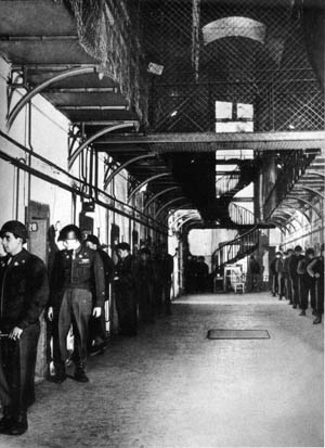 Allied guards watch individual prisoners in their cells inside the Palace of Justice. Wire fencing was erected in common areas to deter suicide attempts by the inmates.