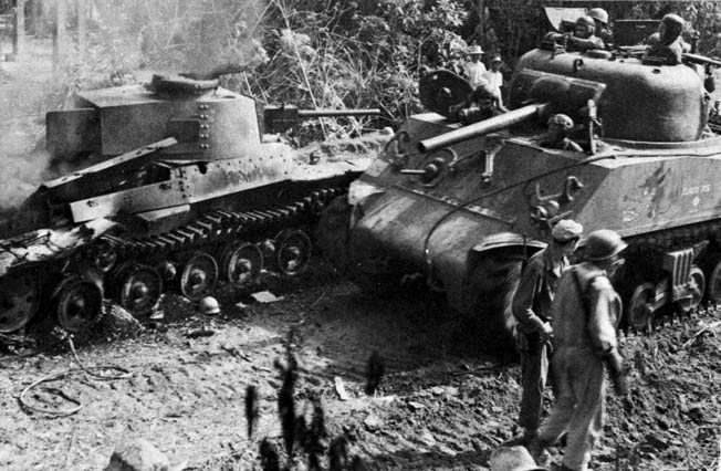 An M4A3 Sherman medium tank named “Classy Peg” passes the hulk of a destroyed Japanese tank on Luzon on January 17, 1945. 