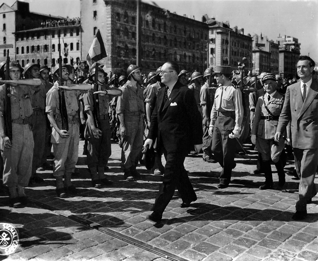 Dignitaries and French officers review troops assembled in the city after the liberation of Marseilles. General Jean de Lattre de Tassigny, commander of the French Army’s 2nd Corps, walks second from right in the procession.