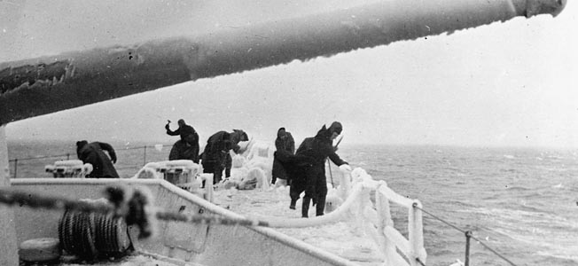 Crew members attempt to clear the ice from the frozen deck of their destroyers.