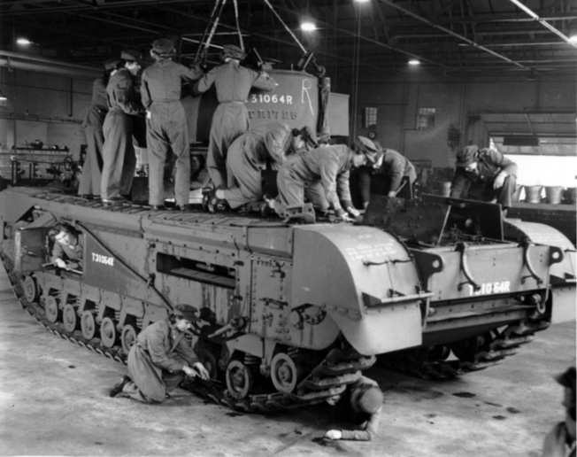 Women of the Auxiliary Territorial Service (ATS) work to guide a Churchill tank's turret into position at a Royal army Ordnance Corps depot.