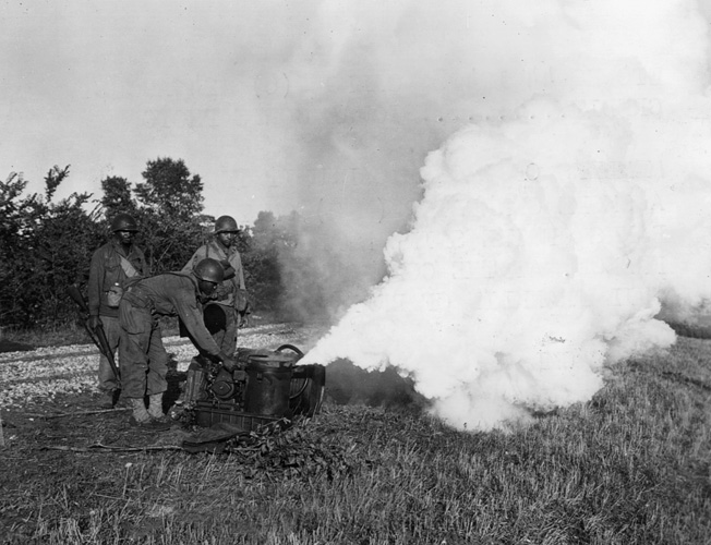 Testing an M-2 smoke generator along the banks of the Seine River in France, members of the 161st Chemical Company produce a thick pall of oily concealment.