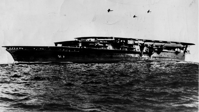An aircraft carrier of the Imperial Japanese Navy is seen underway as aircraft fly in the distance. Losses in carriers, planes, and pilots were irreplaceable for the Japanese, while U.S. strength continued to increase steadily. 