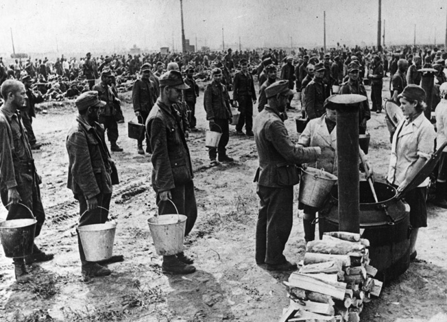 During transit to an internment camp, German prisoners line up to receive a meal from a Red Army field kitchen near Moscow in July 1944.The sheer number of German prisoners needing food and shelter stretched Soviet resources. Note that two of the cooks are women.