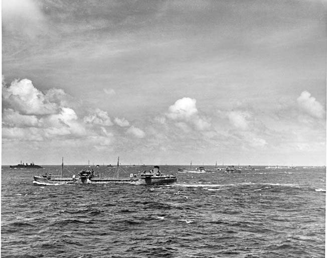 Tankers ride low in the water with their holds full of fuel. By the time this photograph was taken in April 1945, the U.S. Merchant Marine had been delivering precious wartime cargo to island outposts across the Pacific Ocean for more than three years. INSET: Survivors of the sunken Liberty ship John E. Johnson float near a rescue craft. Their cargo ship had been sunk by a Japanese submarine that attempted to ram a raft and lifeboat before surfacing to rake survivors with small-arms fire.