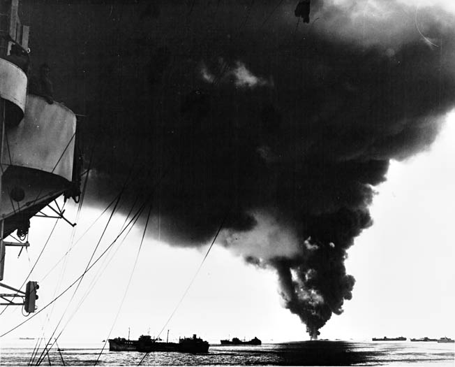 Tankers ride low in the water with their holds full of fuel. By the time this photograph was taken in April 1945, the U.S. Merchant Marine had been delivering precious wartime cargo to island outposts across the Pacific Ocean for more than three years. INSET: Survivors of the sunken Liberty ship John E. Johnson float near a rescue craft. Their cargo ship had been sunk by a Japanese submarine that attempted to ram a raft and lifeboat before surfacing to rake survivors with small-arms fire.