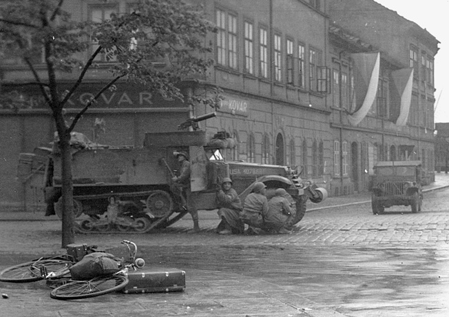 Third Army soldiers pile out of a half-track to search for a German sniper. As German resistance began to crumble, the American found themselves fighting lone snipers and children with antitank weapons.