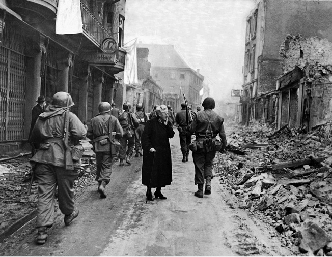 Third Army soldiers march past a German woman in Frankfurt am Main on their way to Czechoslovakia.