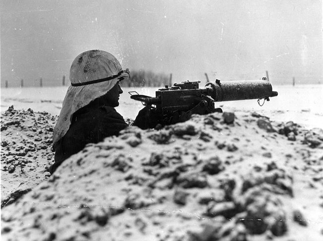 Wearing part of a sheet as camouflage, an American soldier mans a Browning .30-caliber machine gun on the outskirts of the embattled town of Bastogne.
