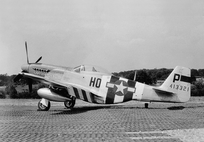 Painted in alternating black and white D-Day invasion recognition stripes, the P-51 Mustang that Major George Preddy flew while scoring most of his kills sits on a runway. Preddy’s planes were named Cripes A’Mighty, a reference to his favorite exclamation while gambling.