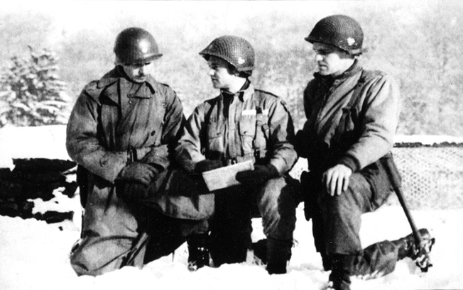 Conferring with other officers of the U.S. 101st Airborne Division near Bastogne, John Hanlon, then holding the rank of major, kneels in the snow at right to survey a map.