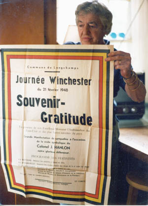 Joan Hanlon, John’s widow, displays a welcoming banner that was produced by the people of Bastogne to commemorate his postwar visit. 