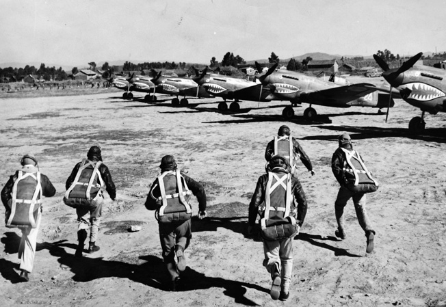 Alert to a coming Japanese air raid, American pilots rush to their P-40s parked at the read on a Chinese airfield.