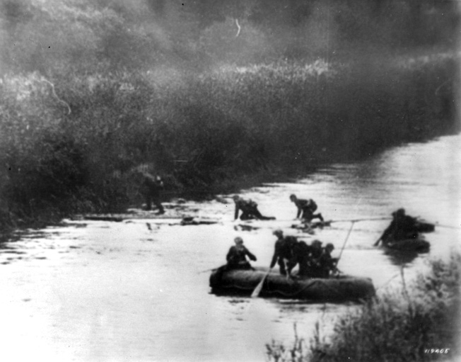 Soldiers of the 7th Panzer "Ghost" Division paddle across the Meuse River, while others scamper over a thin bridge.