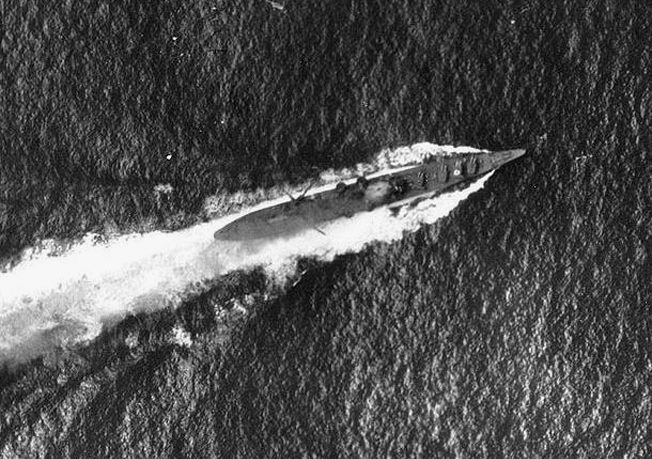 Under attack by American dive-bombers, the Japanese cruiser Chikuma maneuvers violently on October 26, 1942. Damage and a plume of smoke from the impact of a 1,000-pound bomb are faintly visible amidship.