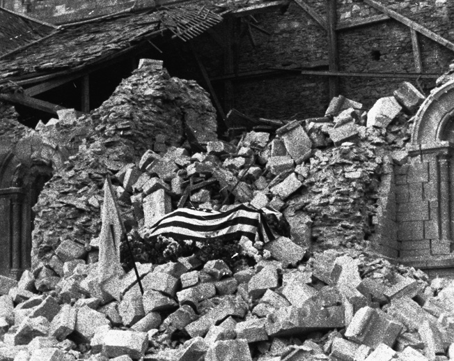 His body draped with an American flag, Major Thomas D. Howie lies in state atop the rubble of a blasted church in the heart of St. Lô.