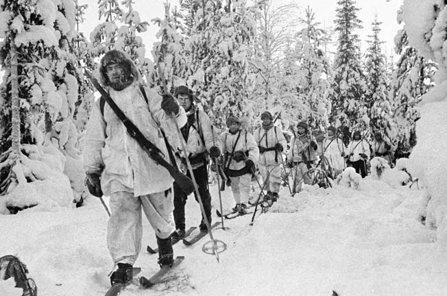 Finnish ski troops, highly mobile in winter warfare, advance through a snow-covered forest. The Finnish troops were highly trained and well equipped.
