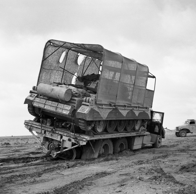 The driver of a British flatbed truck attempts to negotiate the desert sands in March 1942 carrying a Crusader tank covered by the innovative sunshield.