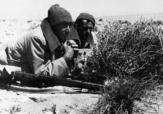 Keeping alert to report enemy movements, a tow-man LRDG team remains concealed behind Axis lines.