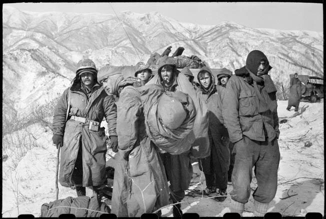 Wounded 7th Infantry Division soldiers and Marines await evacuation during the harrowing retreat from the Chosin Reservoir.