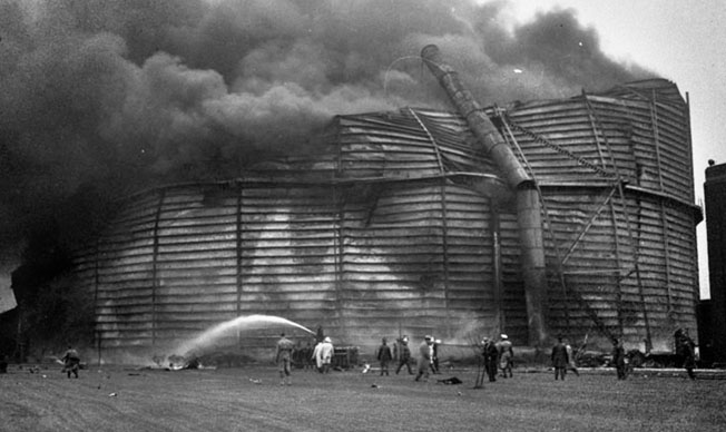 Smoke billows from a 20-million-gallon natural-gas storage tank in Chicago after a B-24 crashed into it on May 20, 1943, killing all 12 men aboard.