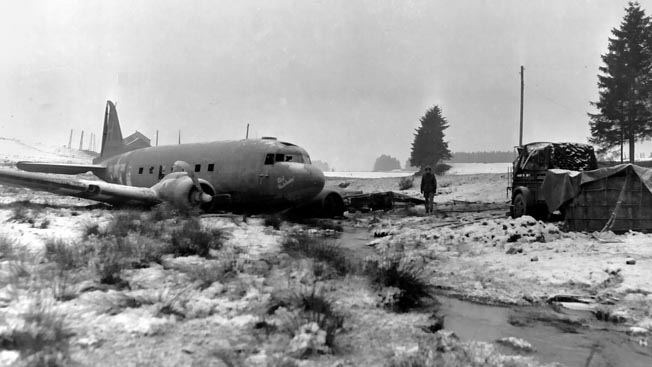 The pilot of a C-47 transport plane crash-landed safely after being shot down during resupply of 101st Airborne units near Bastogne during the Battle of the Bulge.