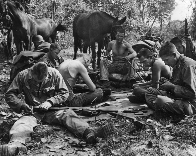 With few roads in the nearly impassable mountainous jungle, troops had to rely on mule power for hauling supplies. Here a group of muleskinners clean their weapons while their animals take a break.