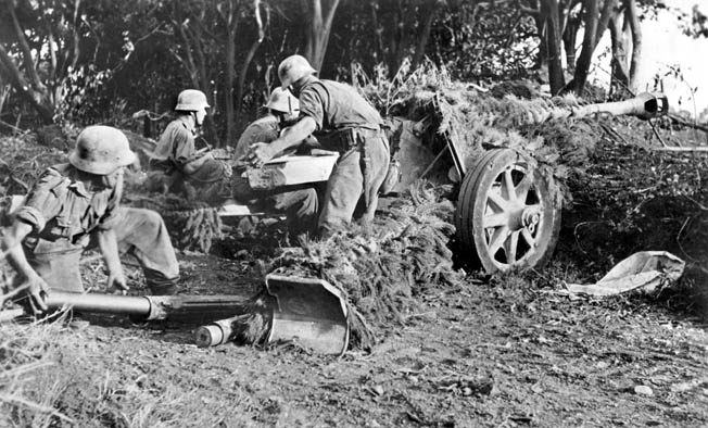 German artillerymen load a camouflaged 75mm antitank gun during the battle. 