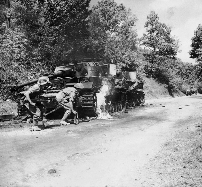 Men of the 2/6th Queen’s Regiment advance past a burning German PzKpfw IV tank in the Salerno area, September 22, 1943.