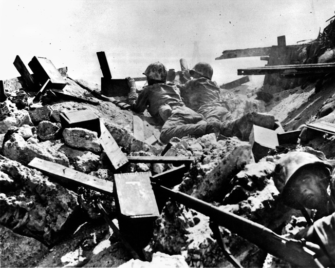 Fear is etched on the face of a Marine (foreground) while a machine-gun team pours fire into the enemy from the rubble of a destroyed Japanese position.