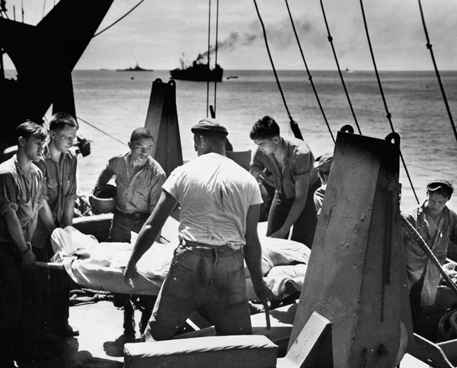 Navy medical personnel aboard a ship gently handle a casualty from the fighting on Tarawa. The wounded will soon be bound for naval hospitals in Hawaii and then California. 